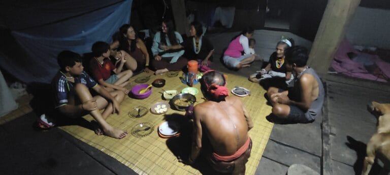 Tour guests sharing a traditional dinner with a Mentawai Sikerei family inside a Siberut uma