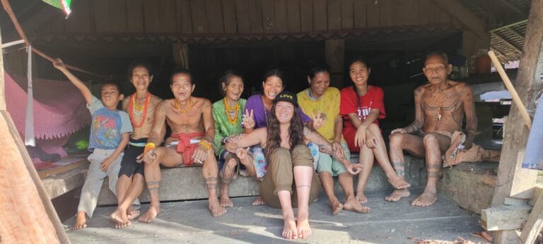 Tour guest in a group portrait with the entire Sikerei family in Siberut village