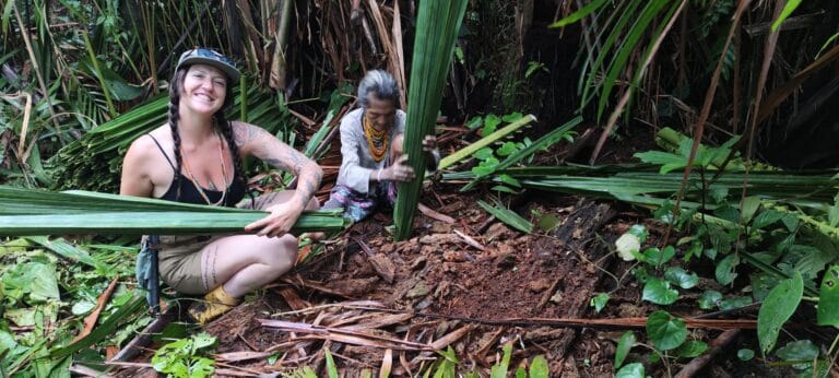 Tour guest harvesting palm leaves alongside an elderly Mentawai woman in Siberut village