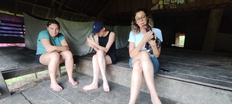 Tour guest holding a chicken inside a traditional uma longhouse in Siberut