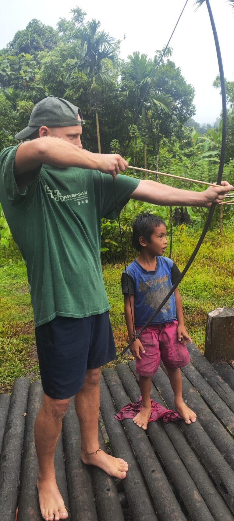 Tour guest practicing traditional Mentawai archery alongside a local boy in Siberut