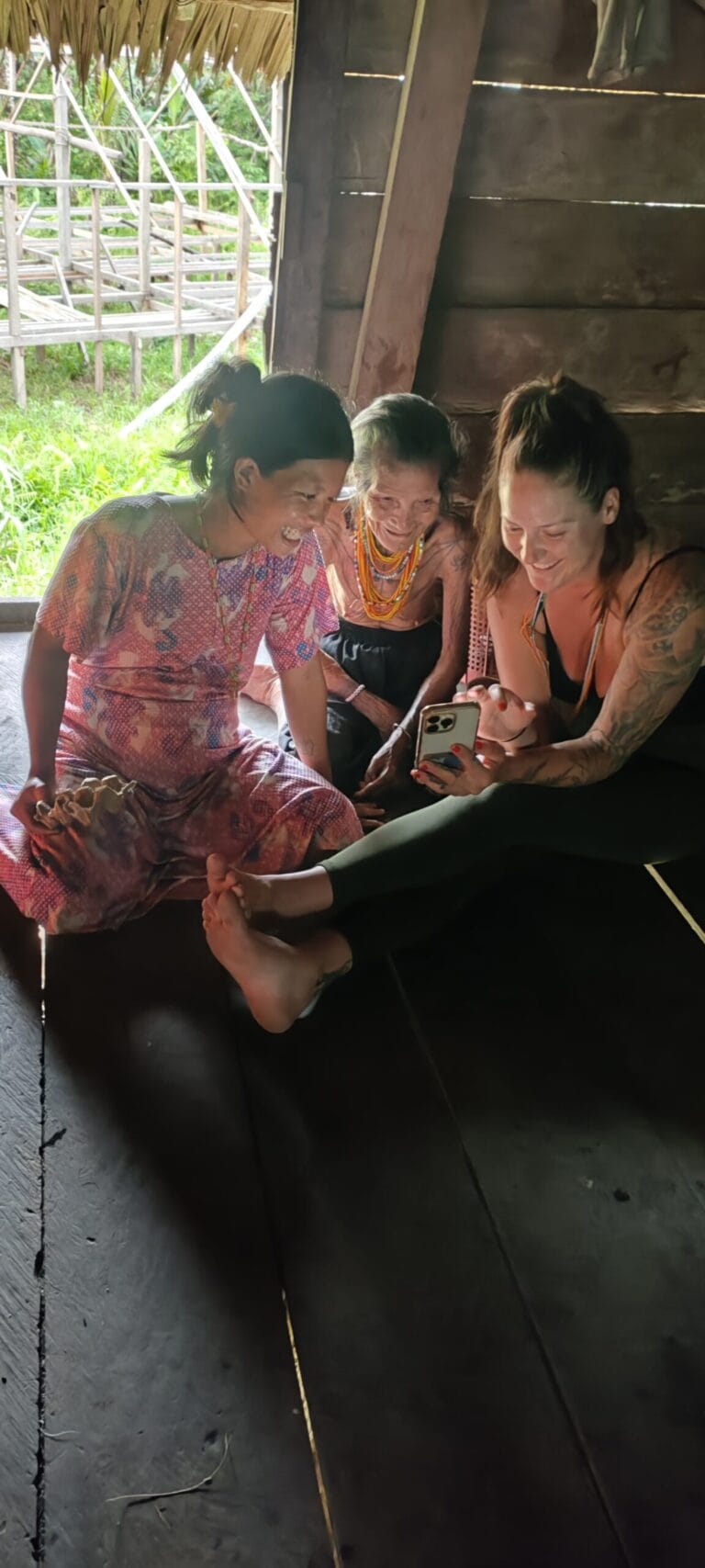 Tour guest sharing phone photos with Mentawai women in Siberut village
