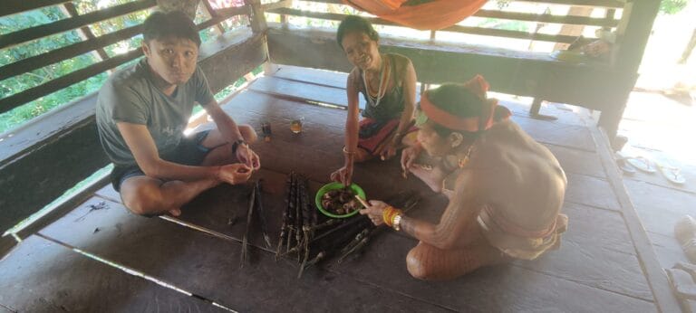 Tour guest sharing a traditional meal with a Mentawai family in Siberut village
