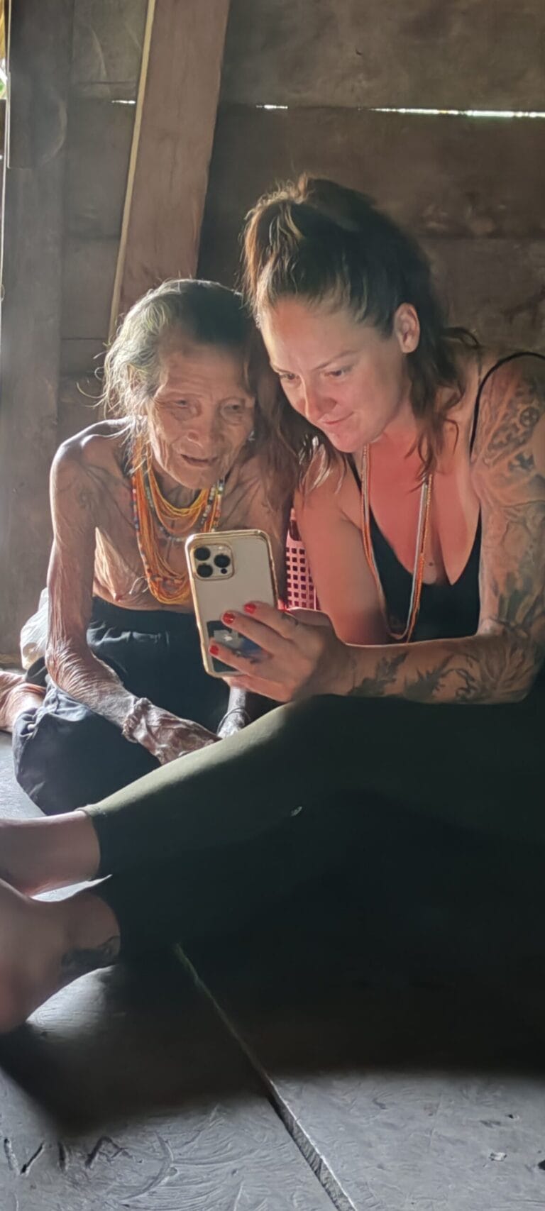 Tour guest showing phone photos to an elderly Mentawai woman in Siberut