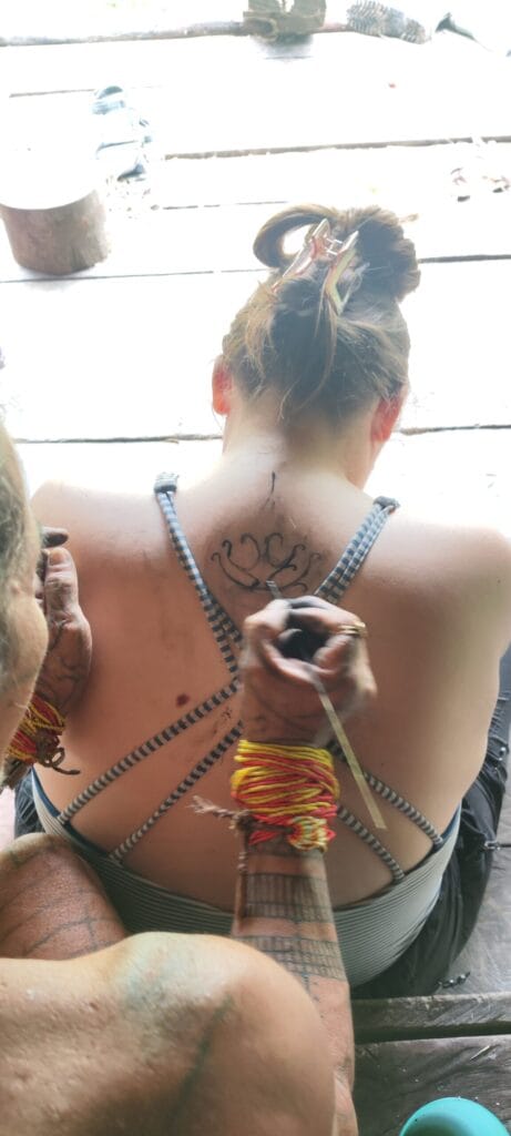 Tour guest sketching a traditional Mentawai tattoo draft using authentic tribal tools in Siberut
