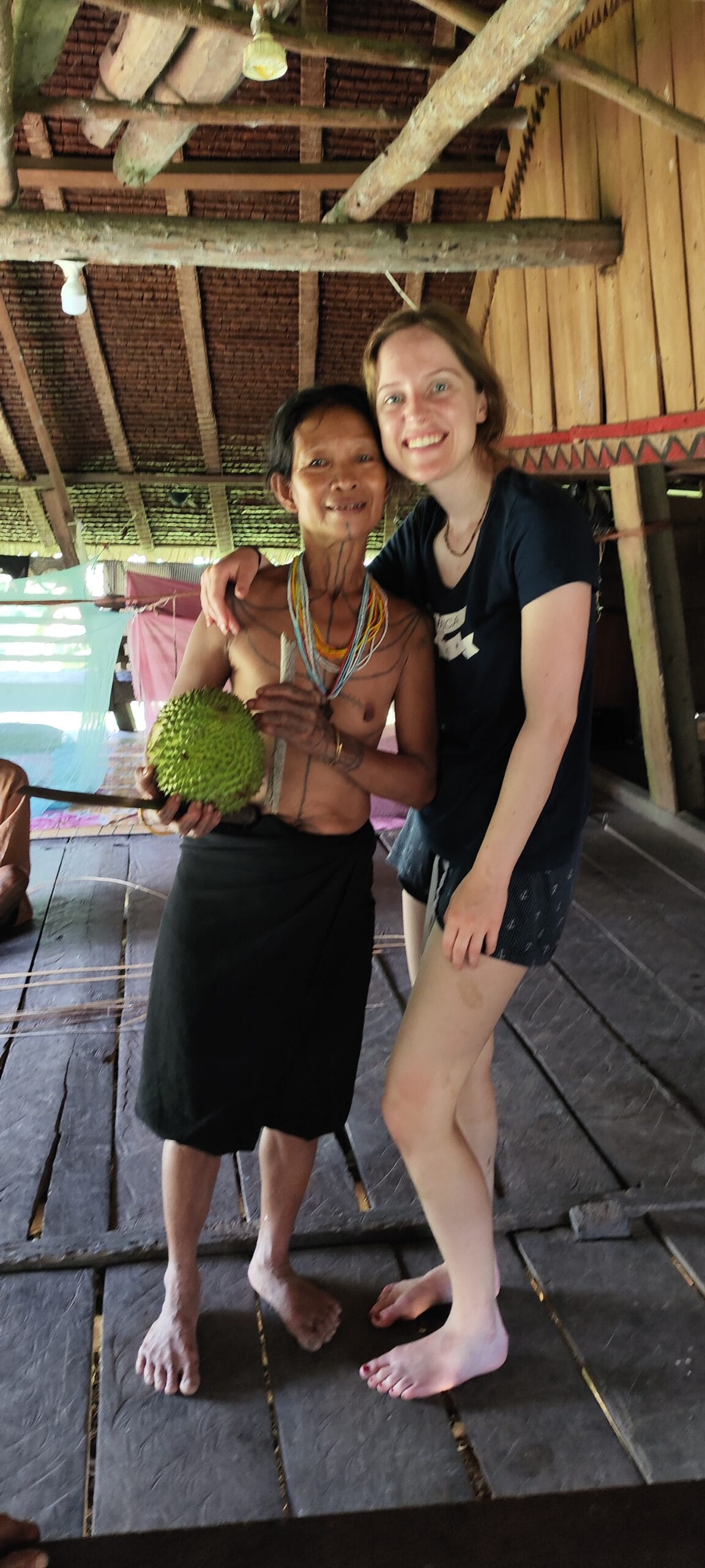 Tour guest with a Mentawai woman holding a freshly picked durian in Siberut forest