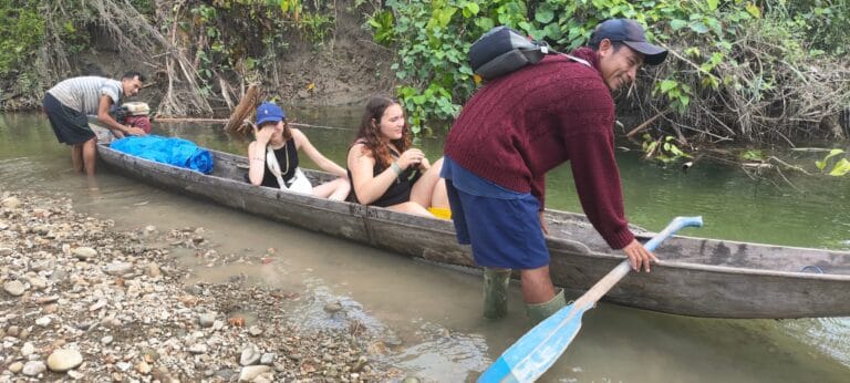 Tour guests crossing a Siberut jungle river by traditional wooden canoe during a Mentawai tribe tour