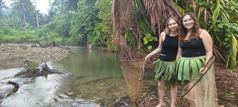 Tour guests wearing traditional Mentawai skirts while river fishing in Siberut