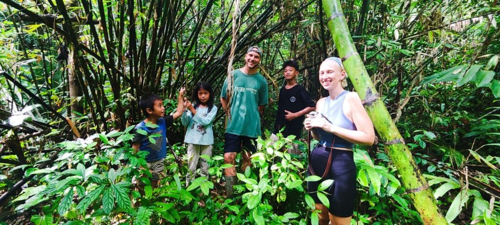Tour guests with local Mentawai children in a bamboo forest in Siberut
