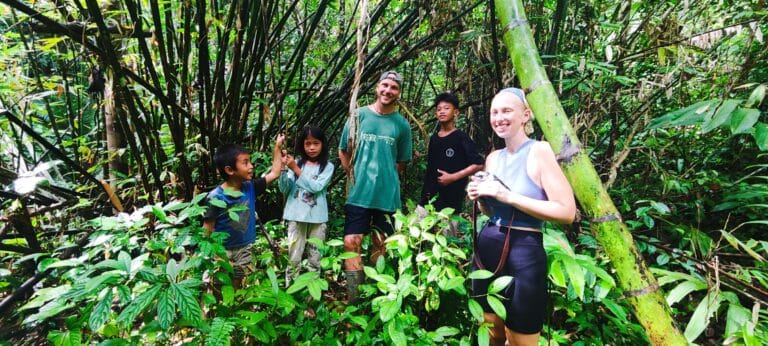 Tour guests with local Mentawai children in a bamboo forest in Siberut