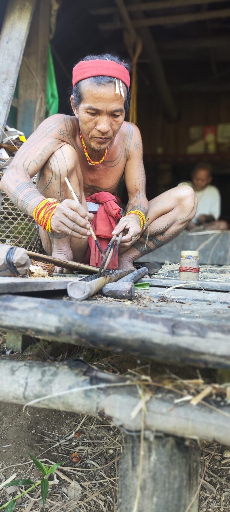 Mentawai Sikerei applying handmade natural poison to wooden arrows for hunting in Siberut