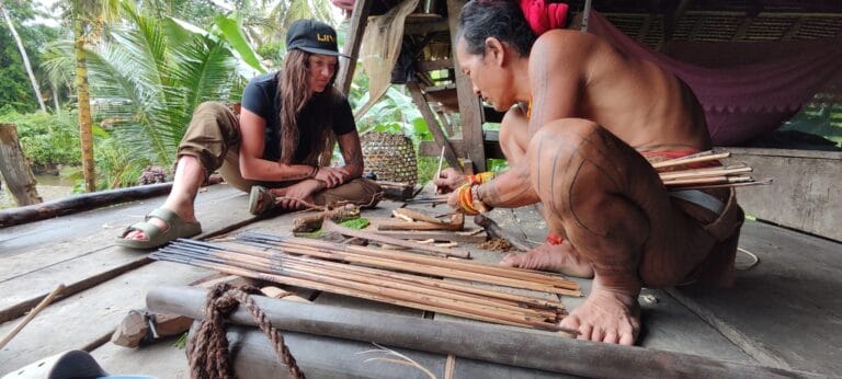 Mentawai Sikerei crafting traditional hunting arrows together with a tour guest in Siberut