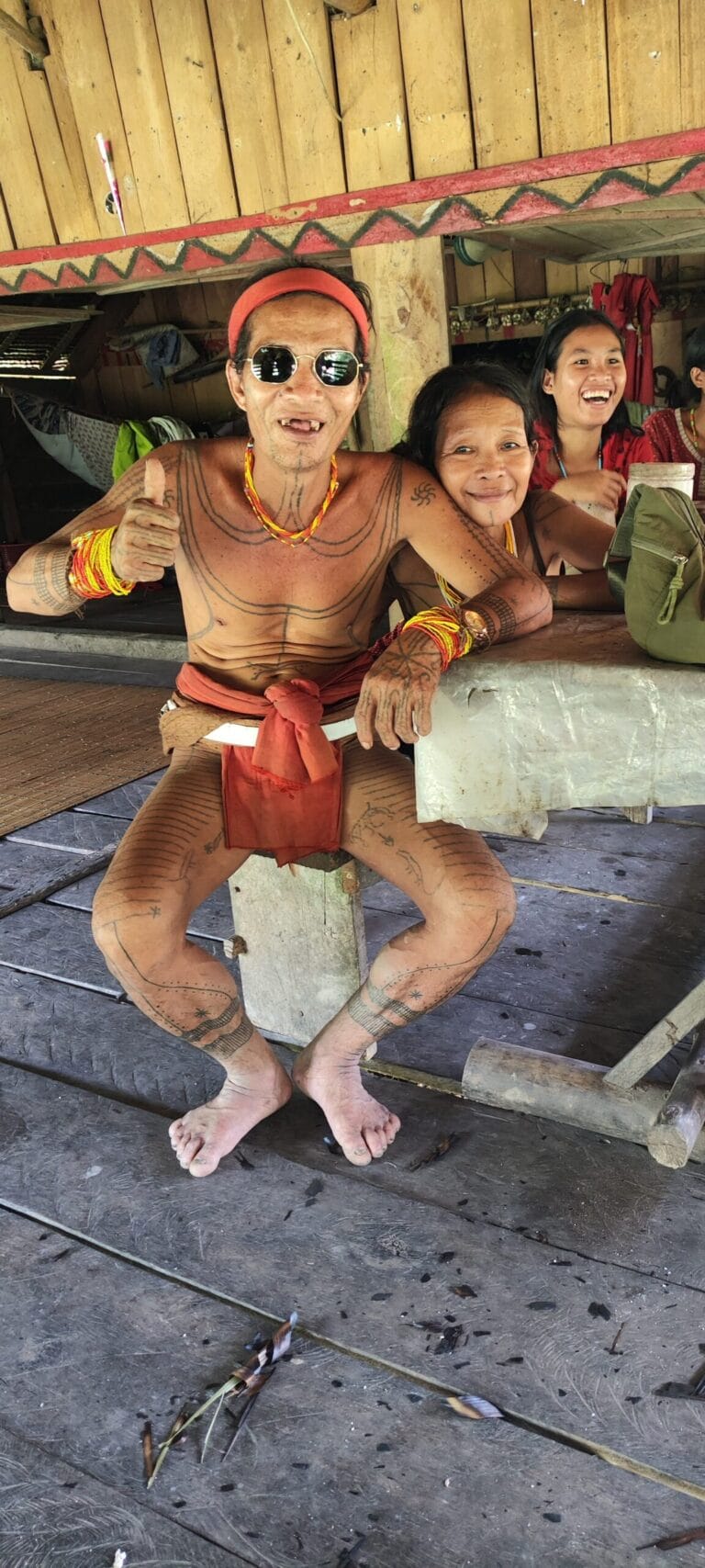 Portrait of a Mentawai Sikerei with his family, showing traditional tribal tattoos in Siberut