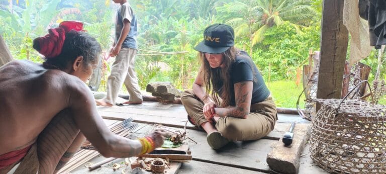 Mentawai Sikerei preparing natural arrow poison ingredients with a tour guest in Siberut