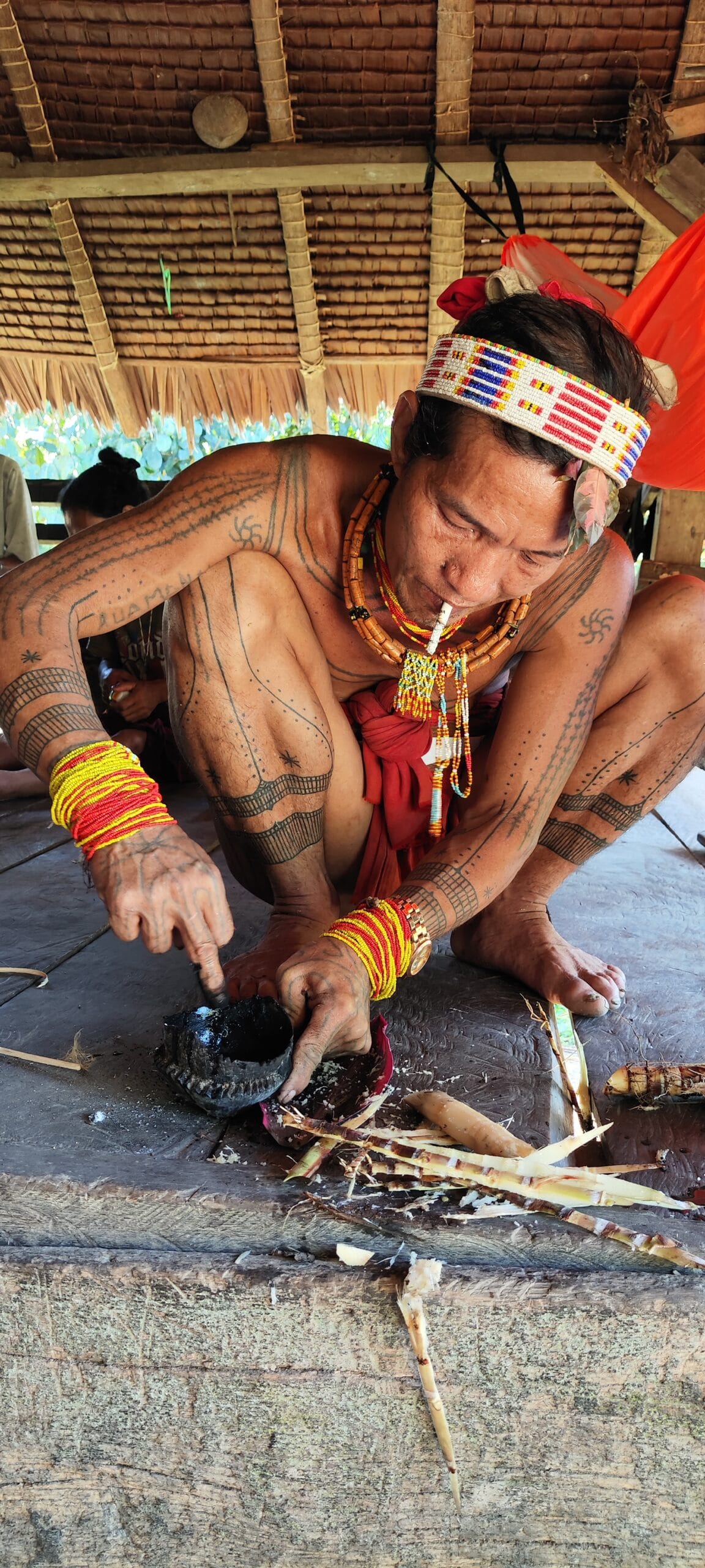 Mentawai Sikerei mixing traditional soot-based tattoo ink in a coconut shell mortar in Siberut