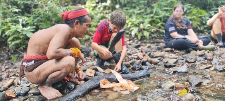 Mentawai Sikerei teaching a guest child how to make traditional tree bark clothing in Siberut village