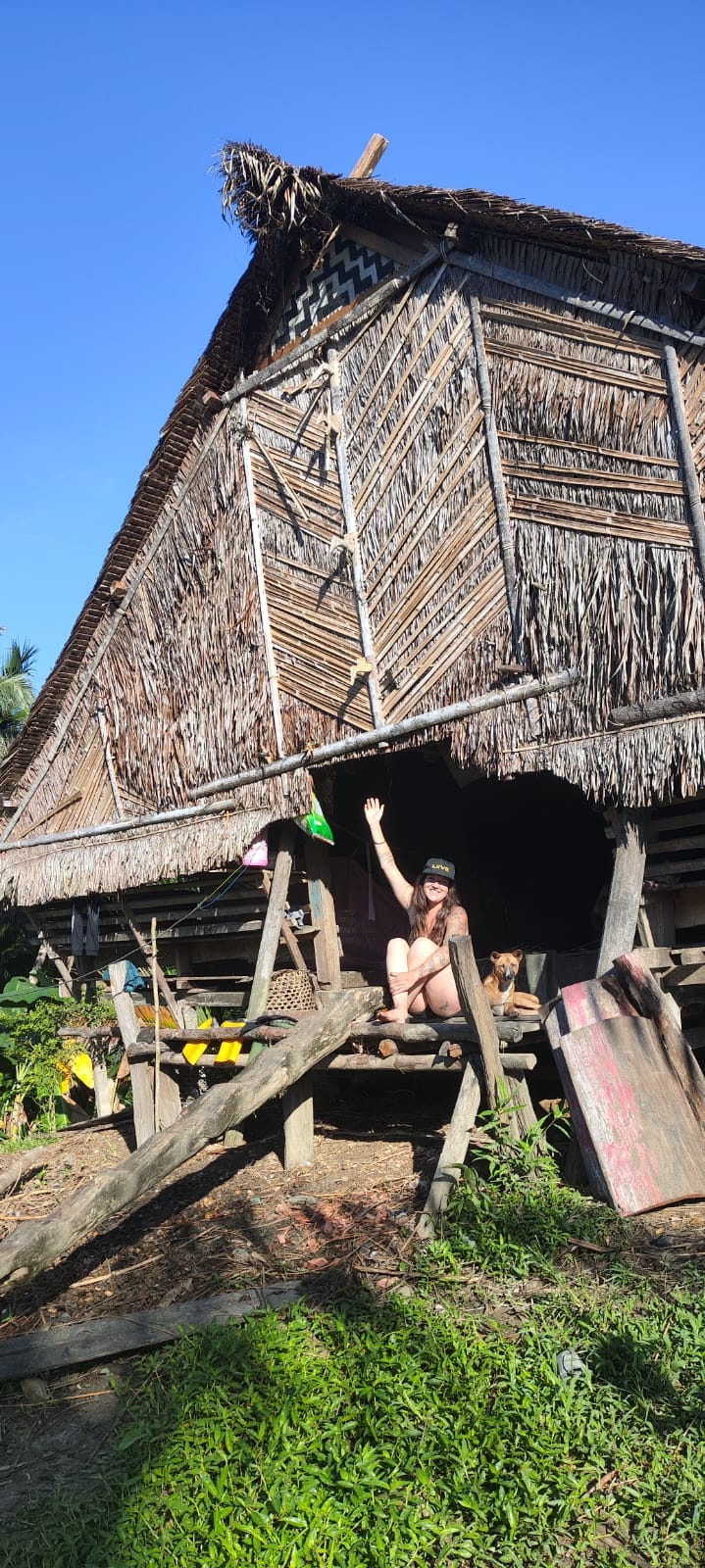 Guest at the entrance of an elevated traditional Uma longhouse, Mentawai