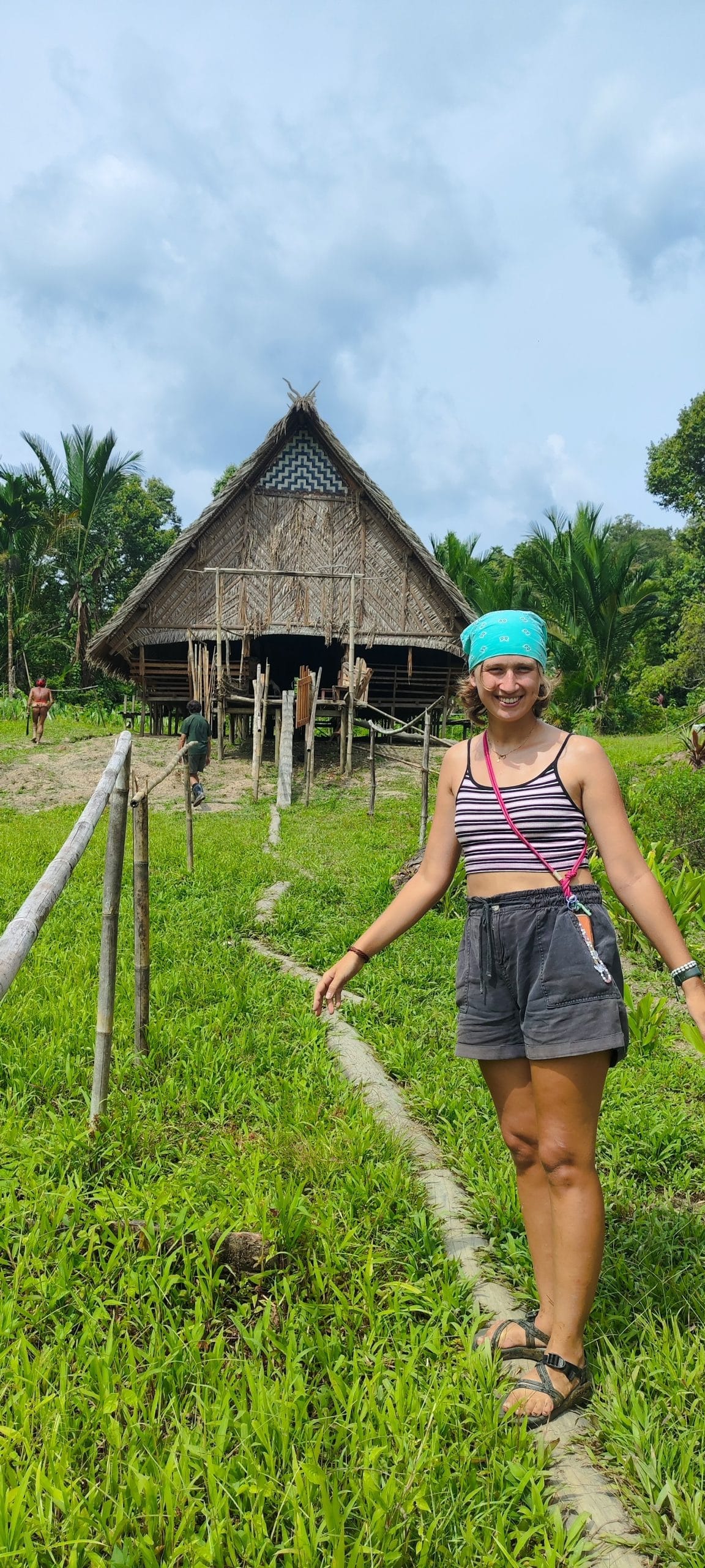 Guest standing in front of a traditional Uma longhouse, Mentawai