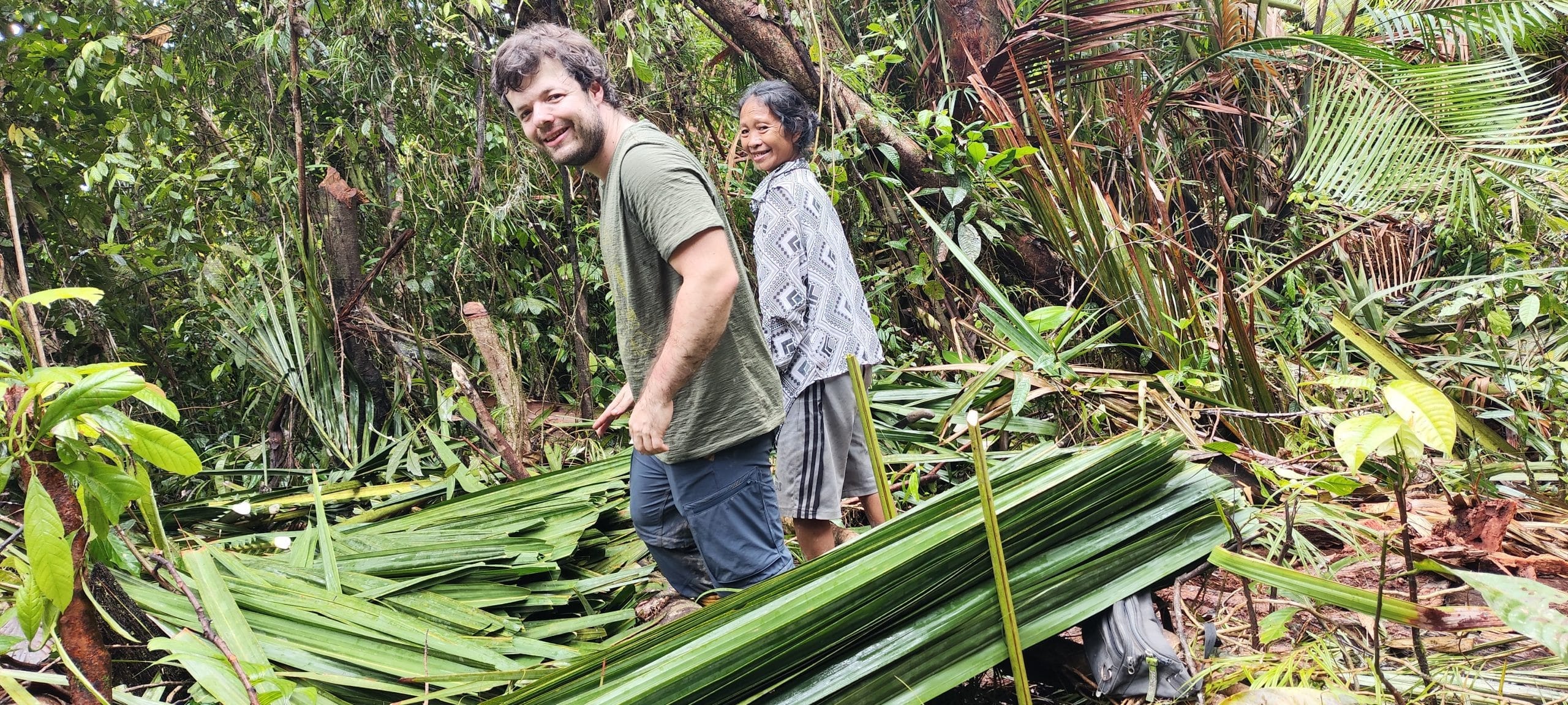 Guest and Mentawai woman collecting sago leaves in the forest