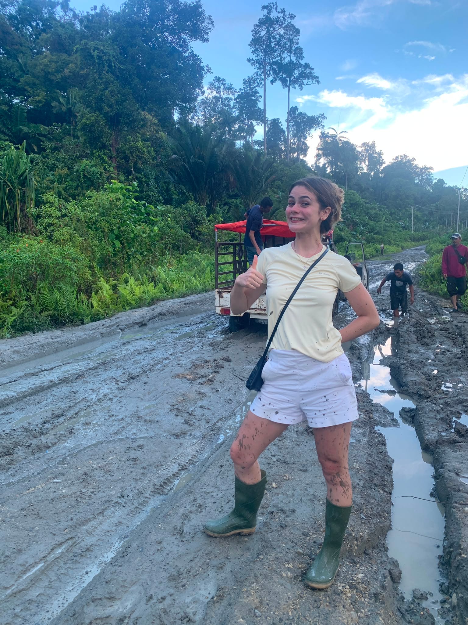 Guest with muddy legs giving thumbs up on the Trans-Mentawai road
