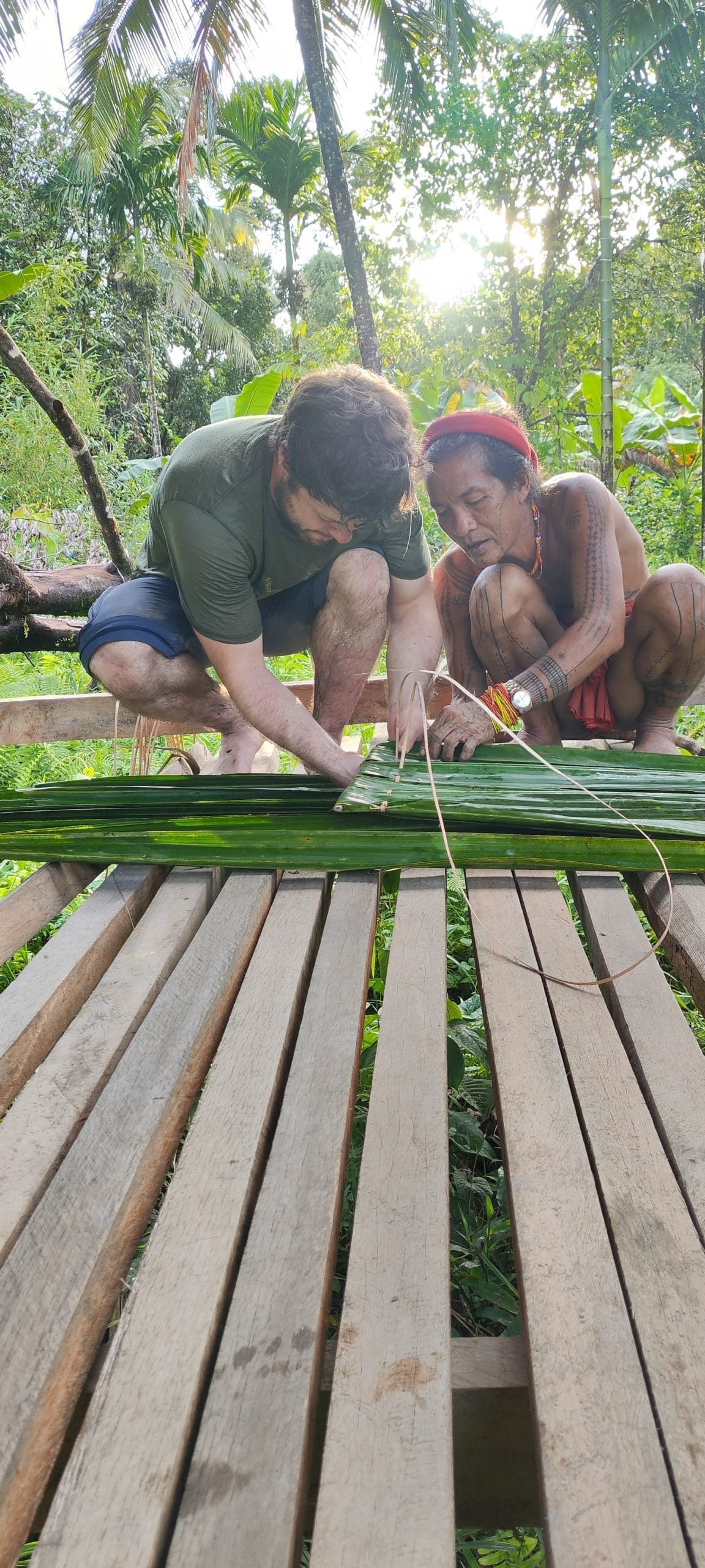 Guest and Sikerei weaving a sago leaf roof panel, Mentawai