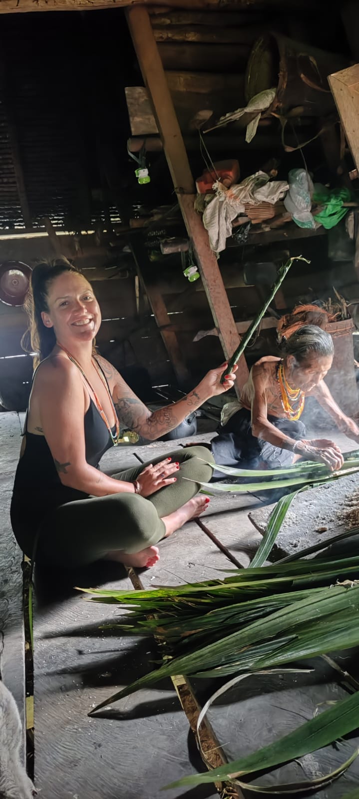 Guest with an elderly Mentawai woman weaving by the fire