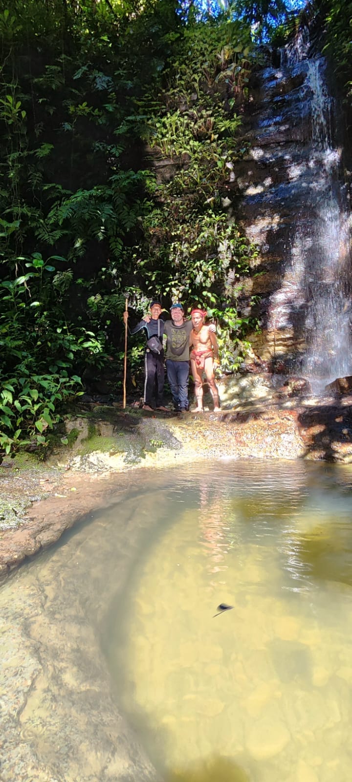 Guests and guide posing at a jungle waterfall pool, Mentawai