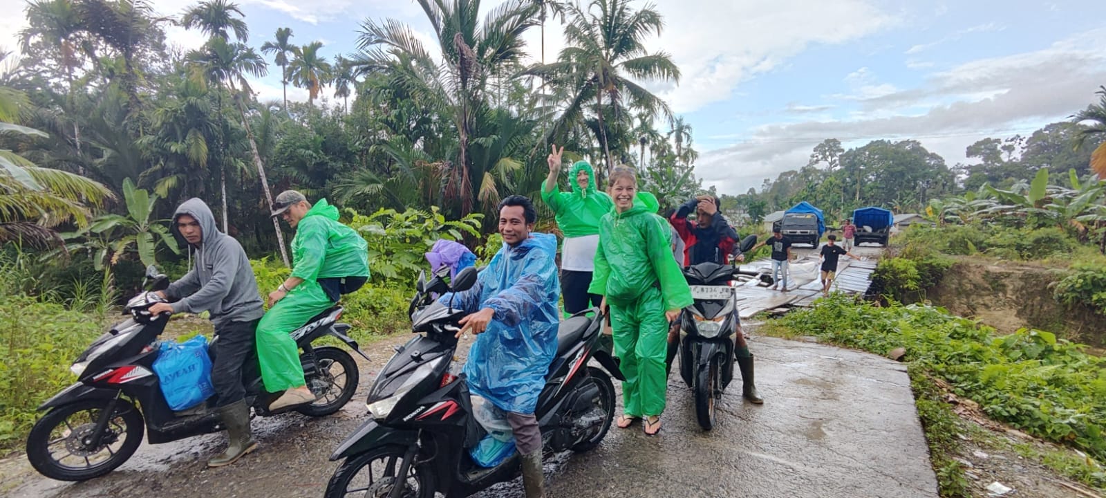 Guests and guides riding a motorbike convoy on a rainy Mentawai road
