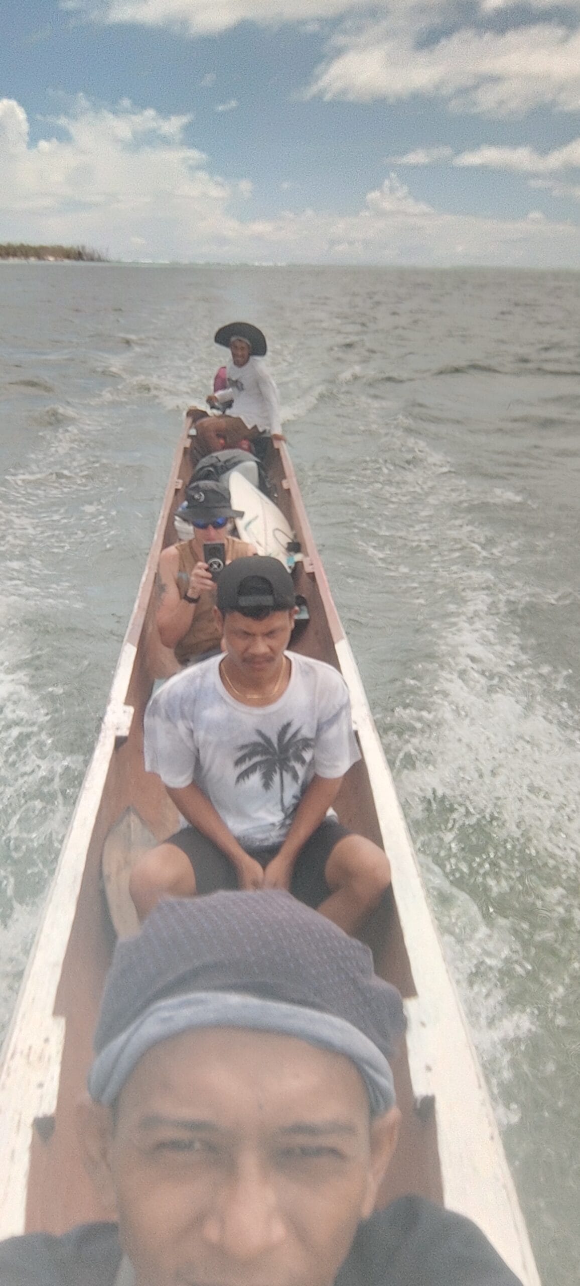 Tour guests on a boat transfer with a surfboard in the Mentawai Islands