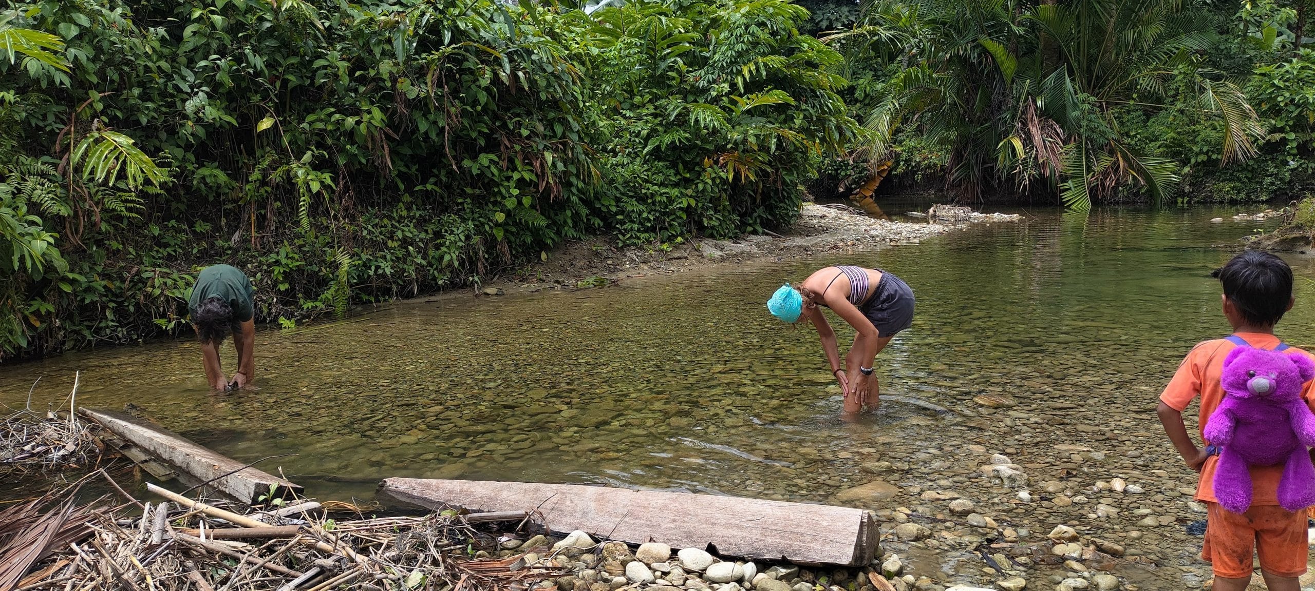 Guests wading in a clear jungle river in Mentawai