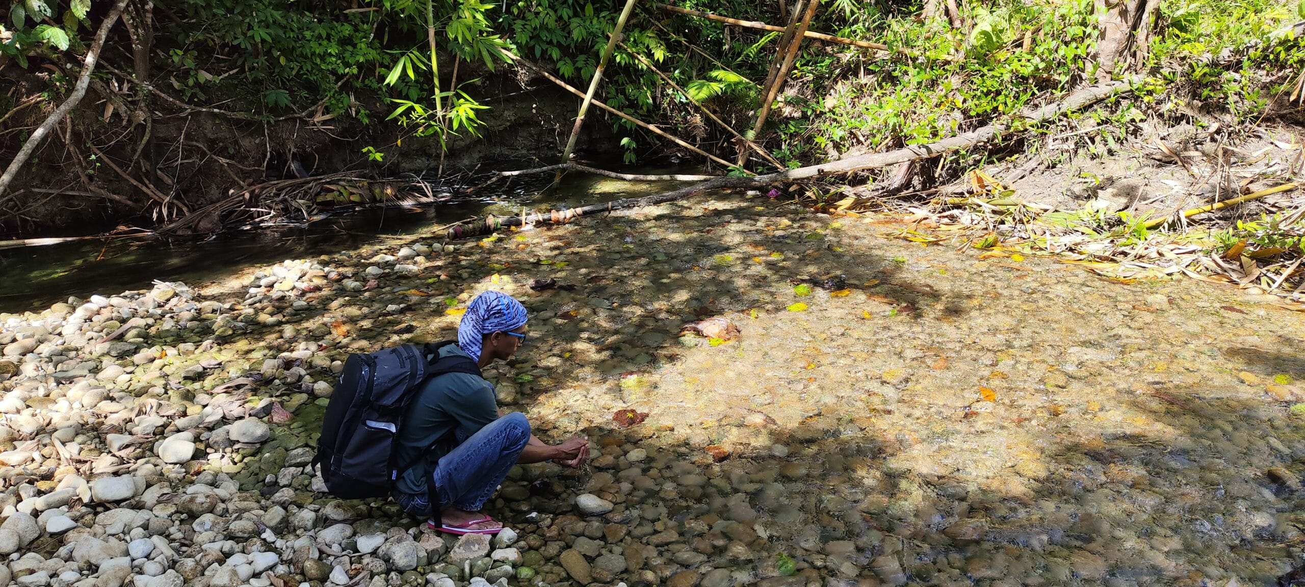 Local guide collecting water from a jungle stream during a Siberut trek