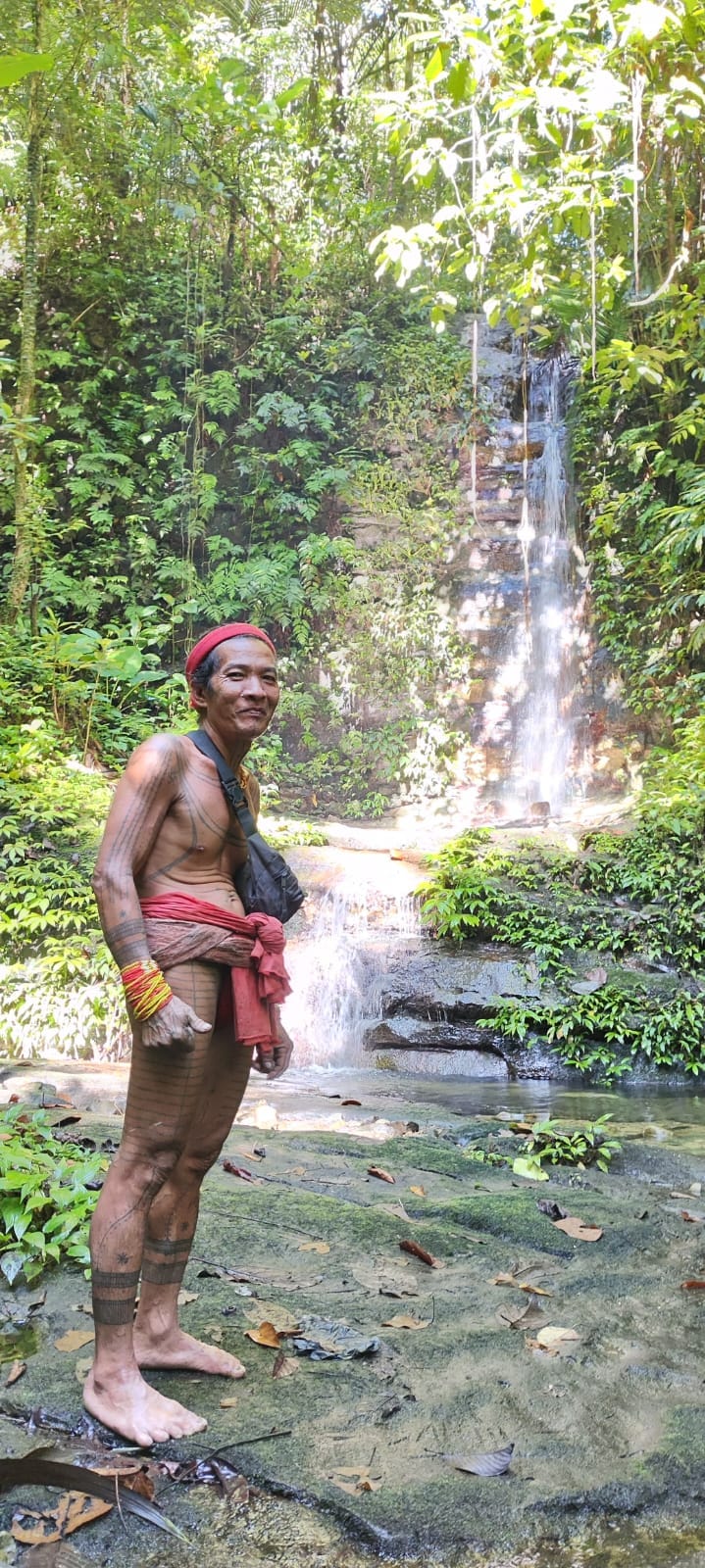 Sikerei full body portrait with traditional tattoos at a waterfall
