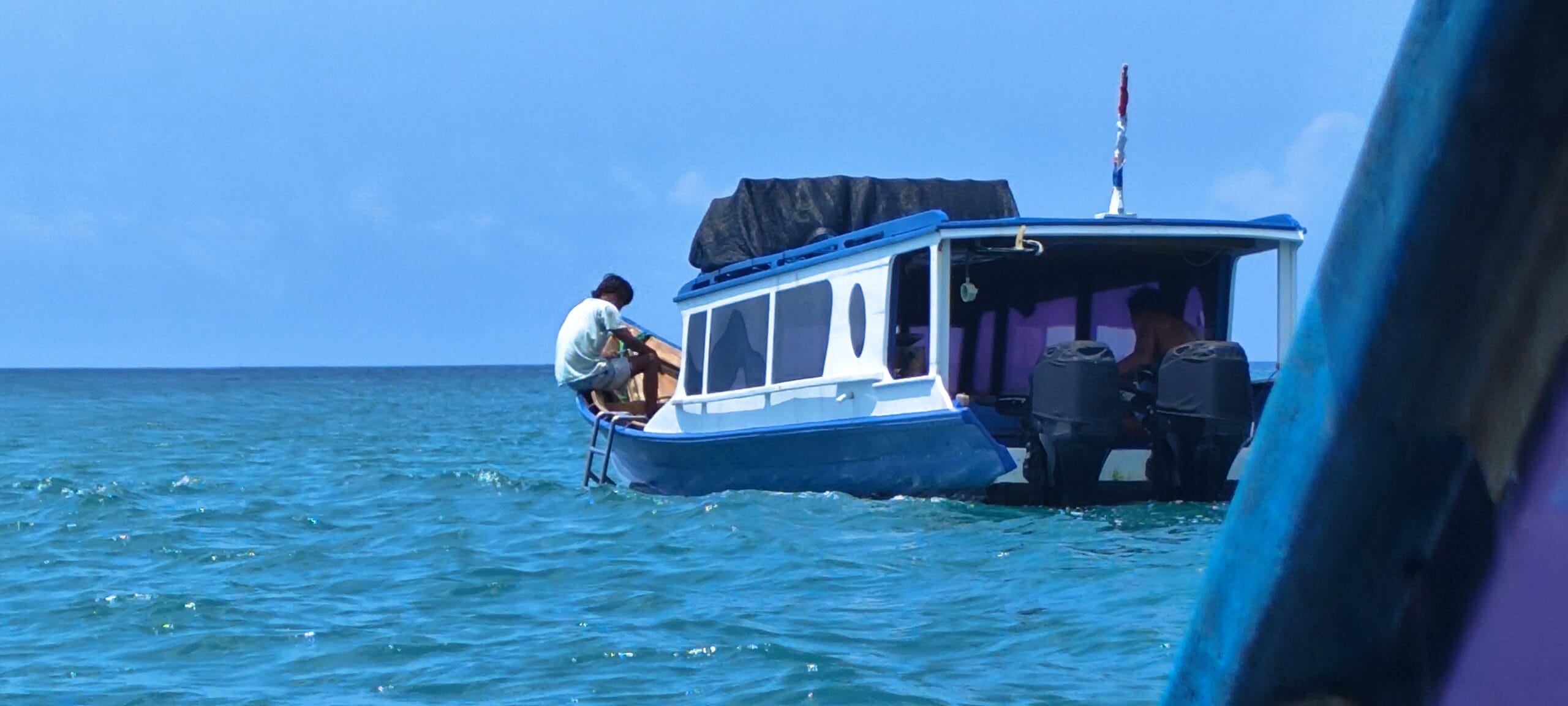 Surf boat crossing turquoise water in the Mentawai Islands