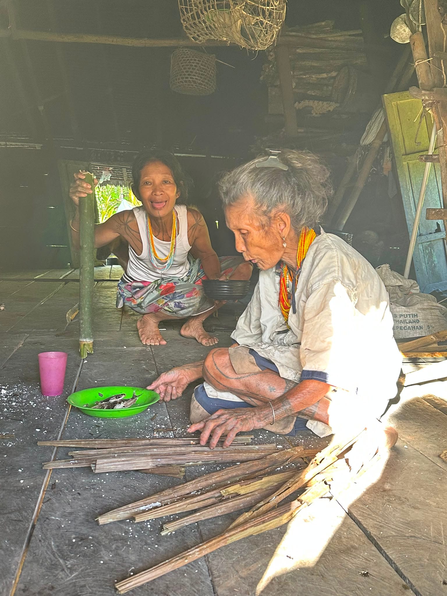 Two Mentawai women preparing fish food inside Uma